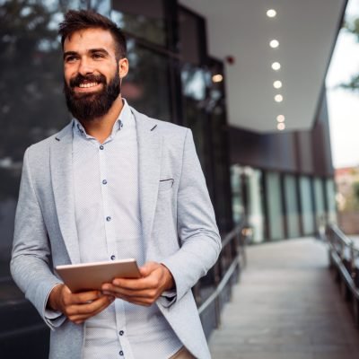 Portrait of young businessman in front of company Portrait of smiling young businessman in front of company